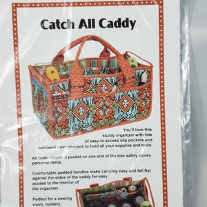 May include: Catch All Caddy organizer with a floral pattern in orange, blue, and white. The tote bag has a handle and multiple pockets. The text on the image says "Catch All Caddy" and "Patterns by Annie".