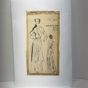 May include: A vintage sewing pattern for a wrap dress. The pattern is printed on a yellowed piece of paper and features a line drawing of a woman wearing the dress. The pattern is titled "Quickest Holiday Sewing - Adele Simpson's Delicious Wrap" and includes the pattern number M 234, sizes 8-18.