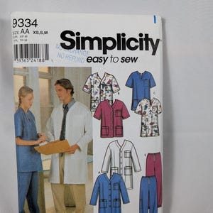 May include: Simplicity sewing pattern 9334 for scrubs in size AA XS, S, M. The envelope features illustrations of various scrub tops and trousers in blue, pink, white, and patterned fabrics, along with a photo of two people wearing medical uniforms.