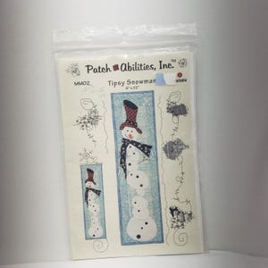 Könnte beinhalten: Ein Quiltmuster für eine schräge Schneemann-Wandbehänge. Das Muster stammt von Patch Abilities, Inc. und misst 15,24 cm x 55,88 cm.