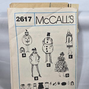 Puede incluir: Patrón de costura vintage McCall's, número 2617, con diseños de disfraces. Las ilustraciones incluyen una calabaza, un muñeco de nieve, un crayón y un vestido de hojas. El patrón está impreso en papel crema con tinta azul y negra.