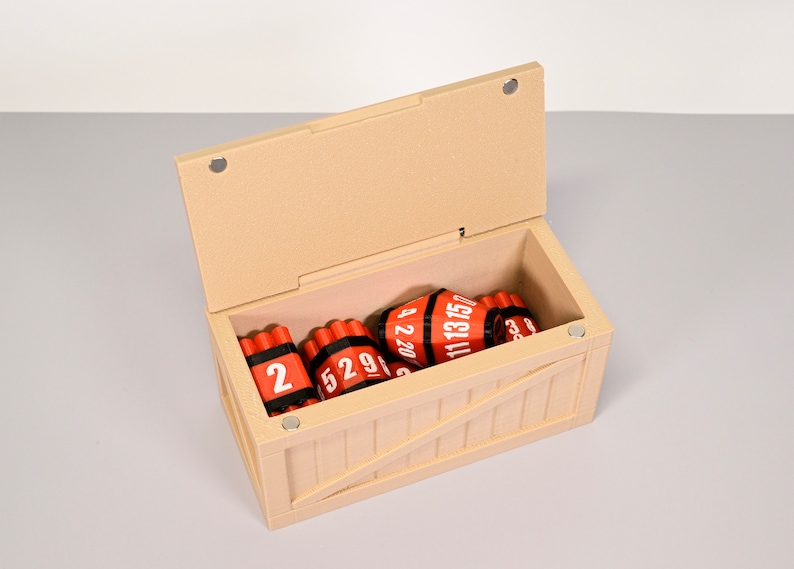 Puede incluir: Una caja de madera con una tapa con bisagras, abierta para revelar un conjunto de palos de dinamita rojos con bandas negras y n&uacute;meros blancos. Los palos est&aacute;n etiquetados con "2", "529", "4 2 20", "11 13 15" y "623".