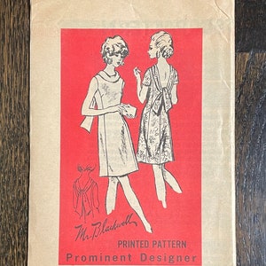 May include: Vintage sewing pattern with illustrations of dresses on a red background. The pattern is labelled "Mr. Blackwell, Prominent Designer" and size 12. The paper has a worn, aged appearance.