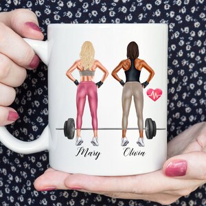 May include: White ceramic mug with a colorful illustration of two women lifting weights. The women are wearing workout clothes and have their names, "Mary" and "Olivia", written below them.