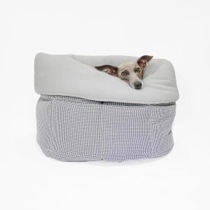 May include: A round pet bed featuring a black and white houndstooth patterned exterior and a soft, light gray fleece interior lining. A small brown and white dog with large ears is resting inside the bed, with its head visible above the rim.