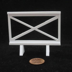 May include: White plastic fence with a criss-cross pattern and two legs. The fence is about the size of a US penny.
