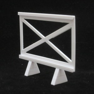 May include: White wooden easel with a simple X-shaped design. The easel has a rectangular frame and two triangular legs.