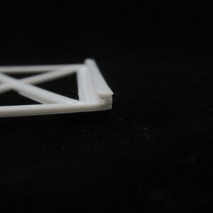 May include: White plastic frame with a criss-cross pattern. The frame is made of multiple layers of plastic.