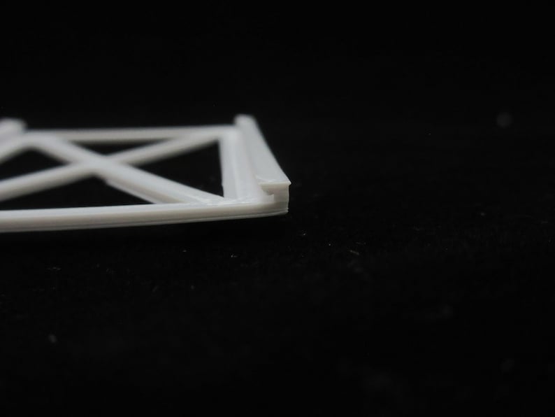 May include: White plastic frame with a criss-cross pattern. The frame is made of multiple layers of plastic.