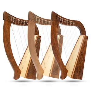 Könnte beinhalten: Drei hölzerne keltische Harfen mit aufwendigen Schnitzereien und Saiten. Die Harfen sind in einer Reihe angeordnet, wobei die größte Harfe hinten und die kleinste Harfe vorne ist.