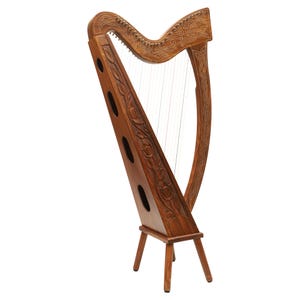 May include: A wooden harp with intricate carvings and strings. The instrument has a dark brown finish and a decorative design on the soundboard and frame. The harp stands on three legs.