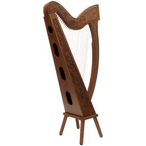 May include: A wooden harp with intricate carvings and a warm brown finish. The harp features a triangular frame with decorative cutouts and a stand with three legs. The soundboard is adorned with floral and Celtic knot designs.