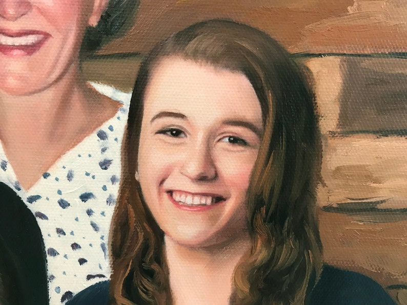 May include: A close-up portrait of a young woman with long brown hair smiling. She is wearing a dark blue shirt and is standing next to an older woman.