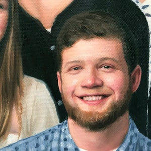 May include: A close-up portrait of a person with a beard and short brown hair. The person is smiling and wearing a blue and white patterned shirt.