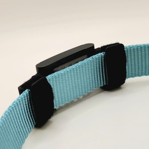 The Fi Series 3 collar adapter is attached to a non-Fi collar using two hook and loop straps with adjustable sliders