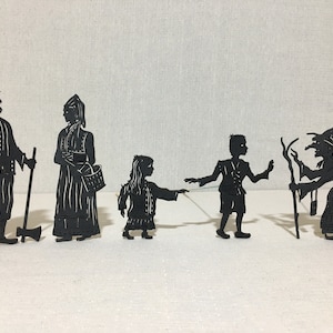 Può includere: Un set di sei figure di silhouette nere, tra cui un uomo con un bastone, una donna con un cesto, una ragazza, un ragazzo e due streghe con scope. Le figure sono fatte di carta o cartone e sono progettate per burattini di ombre.
