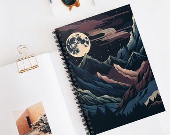 Könnte beinhalten: Spiralgebundenes Notizbuch mit einer Berglandschaft unter einem Vollmond. Die Illustration verwendet Blau-, Lila- und Beigetöne. Das Notizbuch hat eine schwarze Spiralbindung und liegt offen auf einer weißen Oberfläche.