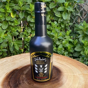 May include: A black cologne bottle with gold accents and the text "Siete Machos Locion Colonia Urania." The bottle has a black cap and a gold label with a detailed illustration. The bottle contains 7.44 fl oz (220 ml).