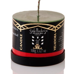 May include: A cylindrical candle with a green top and a black body, featuring gold accents and the text "Siete Machos Veladora Urania." The candle has a red band and a black base. It weighs 3.527 oz.