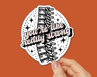 Puede incluir: Una pegatina blanca con una ilustración negra de una columna vertebral y el texto "you're like really strong" en rosa y negro. La pegatina está sujeta por una mano sobre un fondo naranja.
