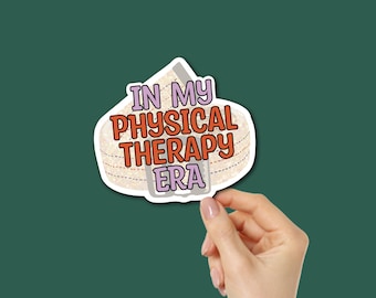 Puede incluir: Una pegatina con el texto "IN MY PHYSICAL THERAPY ERA" en naranja y morado, sobre un fondo beige que simula cinta médica. La pegatina está sujeta por una mano sobre un fondo verde oscuro.