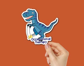 Puede incluir: Una pegatina con un dinosaurio azul de dibujos animados con un patrón de rayas, sosteniendo un objeto amarillo y gris. El texto "Occupational Therapy" está debajo. La pegatina está sujeta por una mano sobre un fondo naranja.