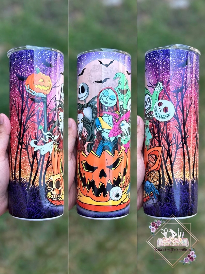 May include: A stainless steel tumbler with a colorful design featuring characters from the Nightmare Before Christmas. The design includes Jack Skellington, Sally, Oogie Boogie, and other characters from the film. The tumbler has a glittery purple and pink background with a black silhouette of trees and a full moon.