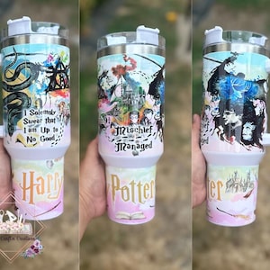 May include: White stainless steel travel mug with a Harry Potter themed design. The mug features a watercolor-style illustration of characters and symbols from the Harry Potter universe, including the Hogwarts castle, a snake, and the words "Mischief Managed". The mug also has a black handle and a white lid.