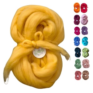 Könnte beinhalten: Ein großes Bündel goldgelber Wollroving, gebunden mit einem passenden Band und einem kleinen Etikett. Das Bild zeigt auch eine Vielzahl kleinerer Bündel farbiger Wollrovinge in Rot-, Lila-, Blau-, Grün- und Brauntönen.