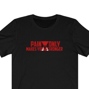 Peut inclure: T-shirt noir avec un texte rouge qui dit "Pain Only Makes You Stronger" avec un graphique de triangle rouge.