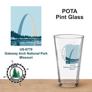 Może przedstawiać: Przezroczysty szklany kufel z grafiką Gateway Arch National Park w Missouri. Projekt zawiera łuk w kolorze niebieskim i pomarańczowym, z tekstem "POTA Pint Glass" i "Parks on the Air". Szklanka jest prezentowana na drewnianej powierzchni.