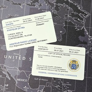 May include: A white card with green text and a map of the United States in the background. The card is an Amateur Radio License for W4OPS, issued to Turner, Mikel K. The license number is 0017364621 and the expiration date is 11-08-2031.