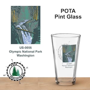 Puede incluir: Un vaso de pinta transparente con una imagen escénica del Parque Nacional Olímpico, Washington. El vaso presenta una cascada y una escena de bosque, con el texto "POTA Pint Glass" y "US-0056 Olympic National Park Washington".