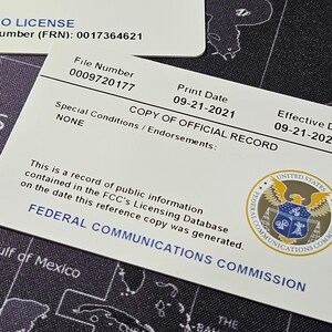 May include: A white card with the text "COPY OF OFFICIAL RECORD" and the seal of the Federal Communications Commission. The card includes the text "File Number 0009720177", "Print Date 09-21-2021", and "Effective Date 09-21-2021".