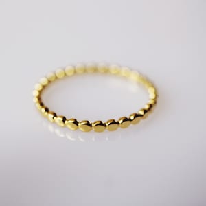 Könnte beinhalten: Ein goldener Ring mit einem Perlenmuster. Der Ring besteht aus kleinen, runden Perlen, die gleichmäßig verteilt sind.
