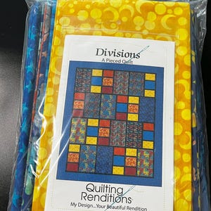 May include: A quilting kit with fabric squares in blue, yellow, and red. The kit includes instructions for a quilt titled "Divisions: A Pieced Quilt" by Quilting Renditions.