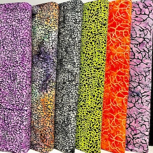 May include: A collection of fabric rolls in various colors, including purple, orange, black, and yellow. Each roll features a unique pattern of irregular shapes or branch-like designs. The fabrics are tightly rolled and displayed vertically.