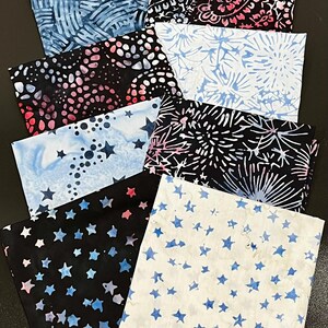 May include: A collection of eight rectangular fabric swatches featuring various batik patterns. Designs include blue and white wavy lines, black with pink and white floral motifs, black with pink dots, light blue with white starbursts, and star prints.