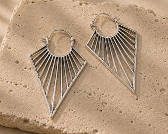 May include: A pair of silver-toned hoop earrings featuring a triangular, fan-like design with radiating thin metal lines. The earrings have a circular top section for attachment and a pointed bottom, showcasing an oxidized finish in the grooves.