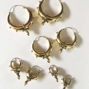 May include: Set of six gold hoop earrings with decorative details. The earrings are of varying sizes, with the largest being approximately 3 inches in diameter and the smallest being approximately 1 inch in diameter.