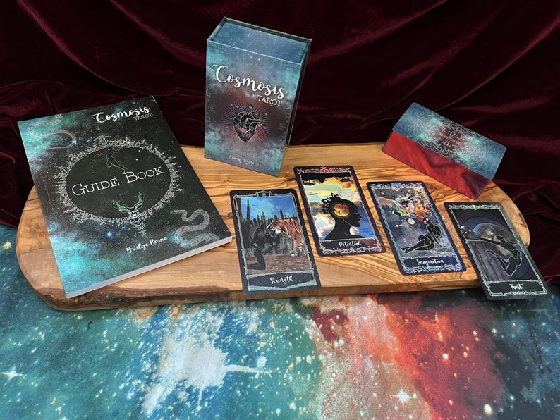 May include: A Cosmosis Tarot deck set including a guidebook, a rectangular storage box, and four tarot cards featuring celestial and surreal illustrations. The cards display the titles Strength, Potential, Inspiration, and Lust in a dark, cosmic color palette.