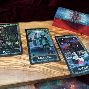 May include: Three rectangular tarot cards with dark, cosmic-themed illustrations and a matching deck box. The cards feature the words Process, Collaboration, and Adaptability in white script. Each card has a decorative border and vibrant, colorful imagery.
