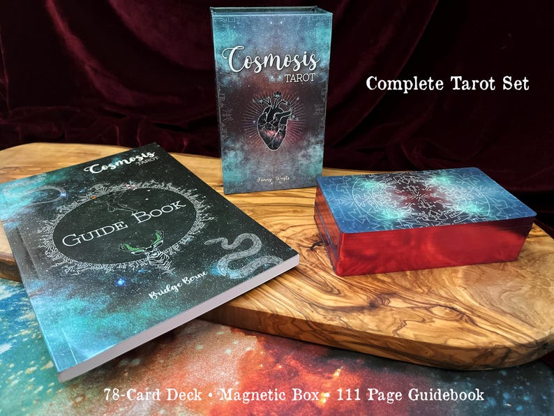 May include: A Cosmosis Tarot set featuring a 78-card deck with red metallic edges, a magnetic storage box, and a 111-page guidebook. The box and book covers display a dark blue and teal nebula design with a central anatomical heart illustration.