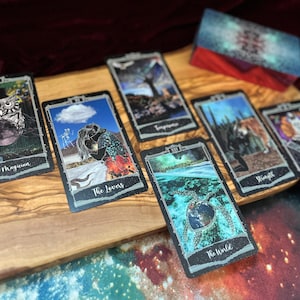 May include: A set of rectangular tarot cards featuring colorful illustrations, including The Magician with an owl, The Lovers, Temperance, The World with a sea turtle, Strength, and The High Priestess, alongside a matching deck box with a nebula pattern.