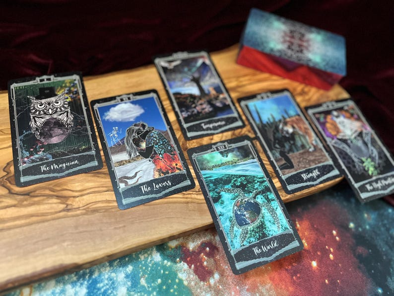 May include: A set of rectangular tarot cards featuring colorful illustrations, including The Magician with an owl, The Lovers, Temperance, The World with a sea turtle, Strength, and The High Priestess, alongside a matching deck box with a nebula pattern.