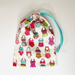Wasserdichte Tasche für nassen Badeanzug aus beschichtetem Baumwollstoff mit 50er-Jahre-Badeanzugmustern in Rosa/Türkis