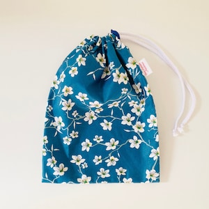 Wasserdichte Tasche für nasse Badeanzüge aus blau beschichtetem Baumwollstoff mit weißem Mandelblütenmuster