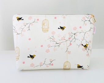 Large toiletry bag in creamy white cotton fabric with Japanese patterns of small cherry blossoms, cages and birds.