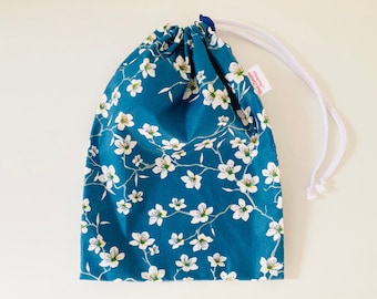 Waterproof bag for wet swimsuits in blue coated cotton fabric with white almond blossom patterns