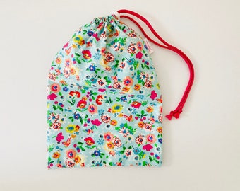 Bolsa impermeable para bañador mojado en tejido de algodón recubierto de color azul con pequeños estampados de flores multicolores